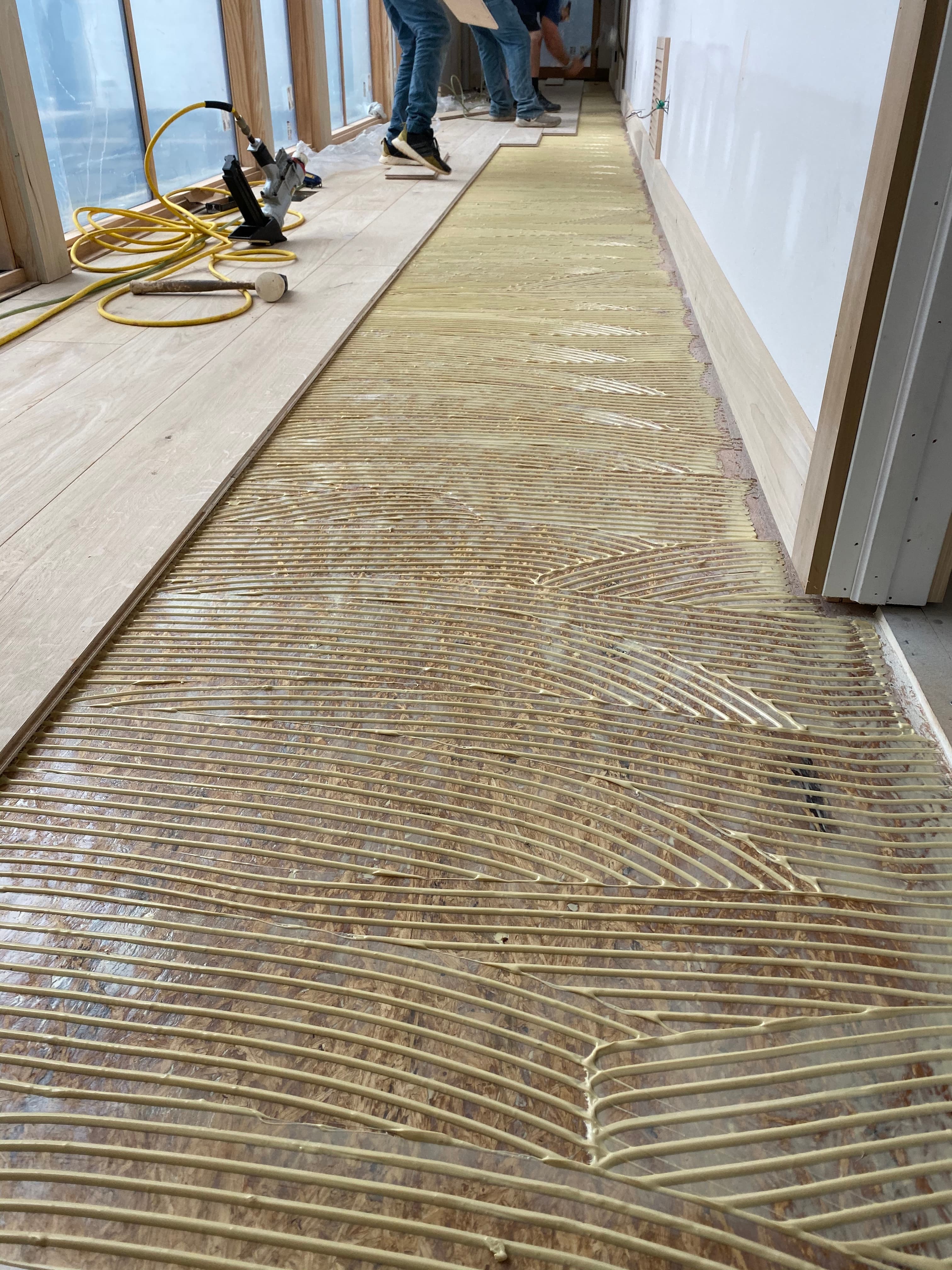 Hardwood floor glue-down installation adhesive trowel detail in hallway Clayton NC