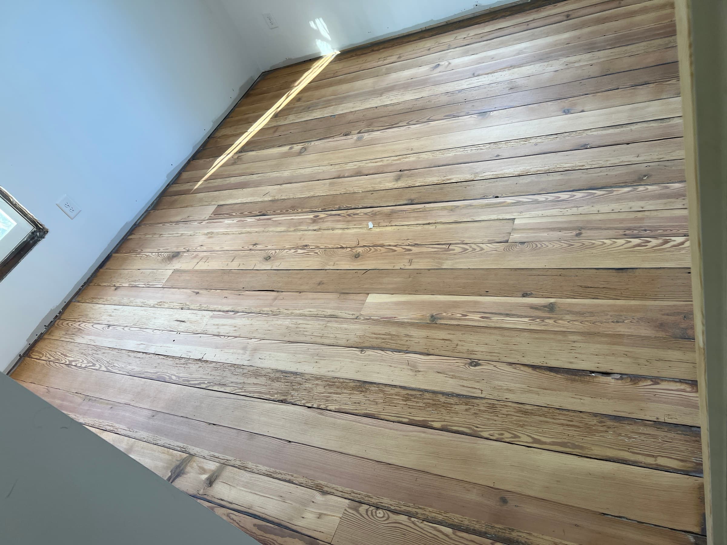 Sanded heart pine floors showing salvaged patch boards integrated alongside originals during refinishing in Morrisville NC