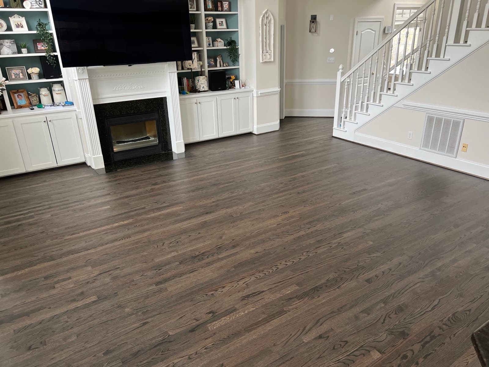 Dark stained hardwood floor living room with fireplace and built-ins